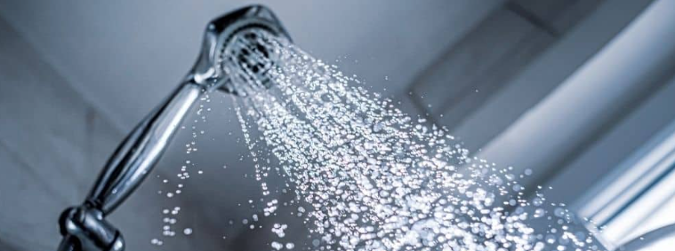 Shower head spraying hard water with mineral deposits in GCC homes